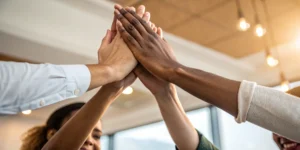 A diverse team joins hands, a result of a successful diversity and inclusion recruiting strategy.